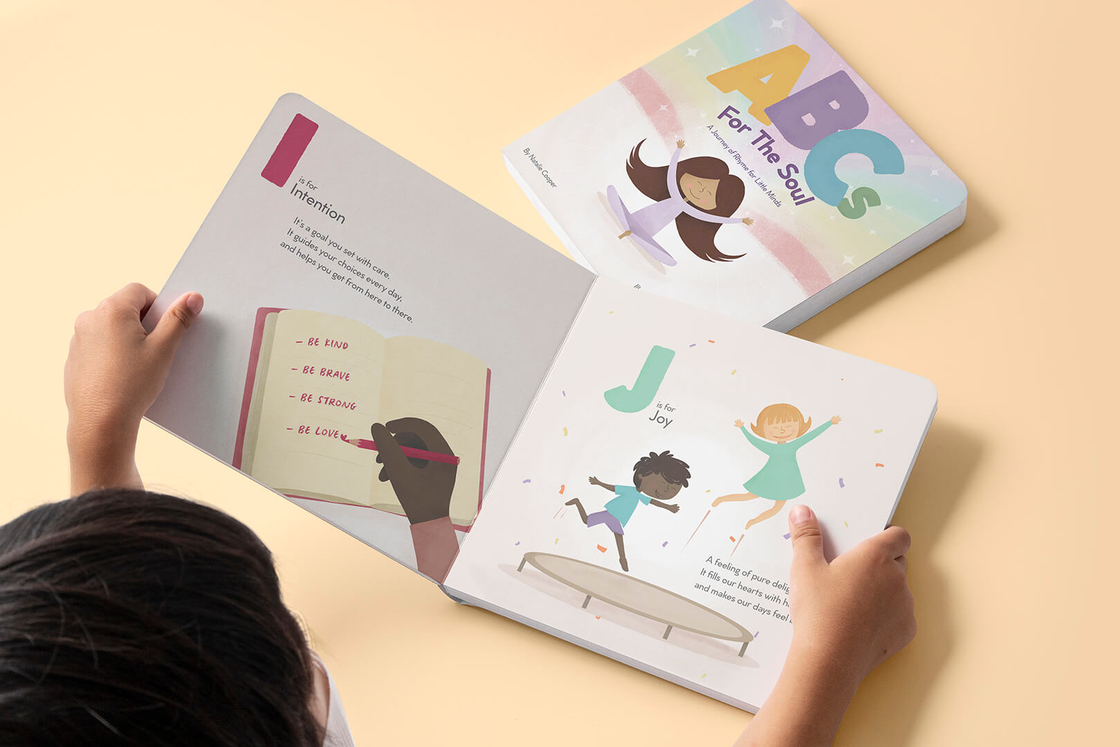 A child holds ABCs for the Soul open to I is for Intention and J is for Joy